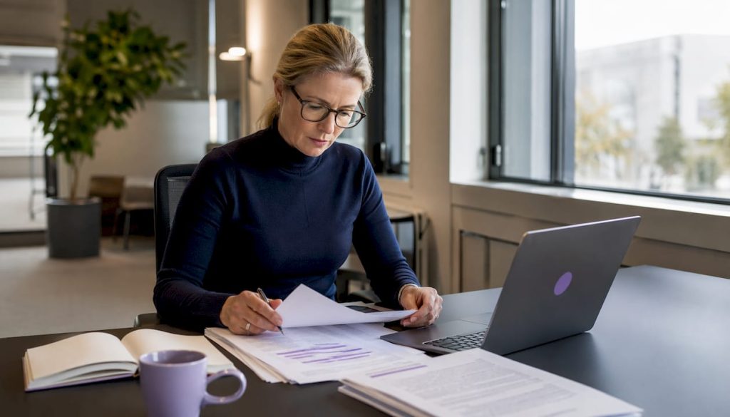 En kvinna går igenom dokument om dataskydd och granskar företagets policyer.